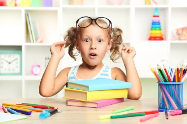 Kitaplar masada oturan küçük kız