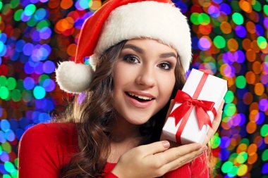 Noel Baba şapkası ışıklar arka plan üzerinde hediye kutusu ile genç kadın