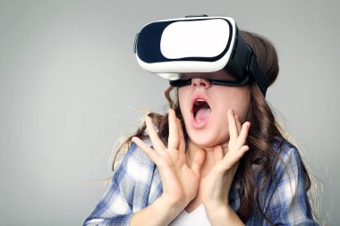 Sanal gerçeklik içinde genç kız gri arka plan üzerinde koruyucu gözlük