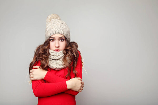 Красивая молодая девушка в шляпе и шарфе на сером фоне
