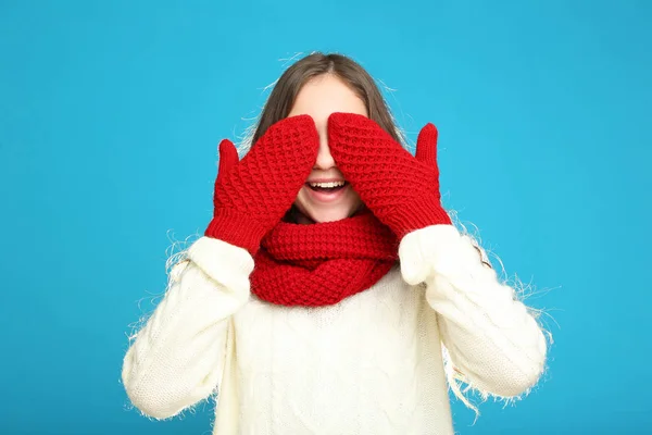 Beautiful young girl in sweater, red gloves and scarf on blue ba — Stock Photo, Image