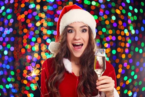 Young woman with glass of champagne on lights background — Stock Photo, Image