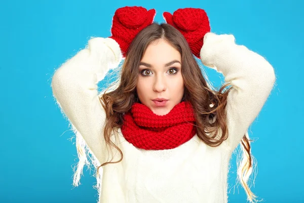 Красива молода дівчина в светрі, червоні рукавички і шарф на синьому ба — стокове фото