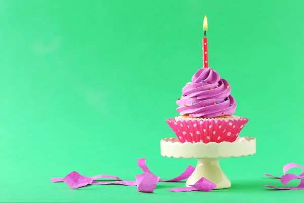 Tasty cupcake with candles on a green background