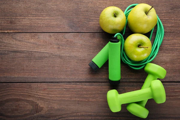 Yeşil elma, ip ve halter ahşap masa üzerinde atlama