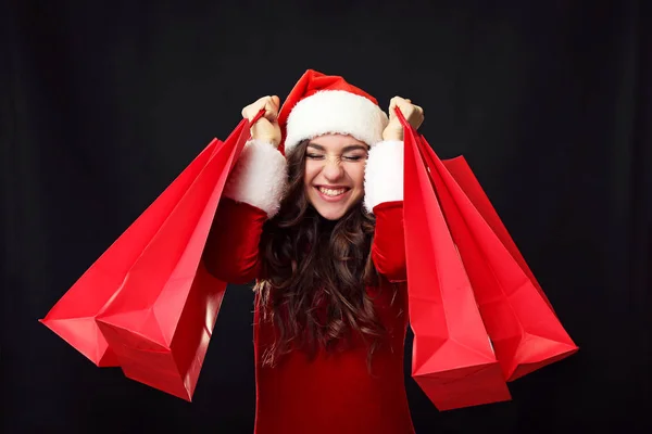 Νεαρή γυναίκα με κόκκινο κοστούμι Χριστουγέννων, κρατώντας τσάντες για ψώνια — Φωτογραφία Αρχείου