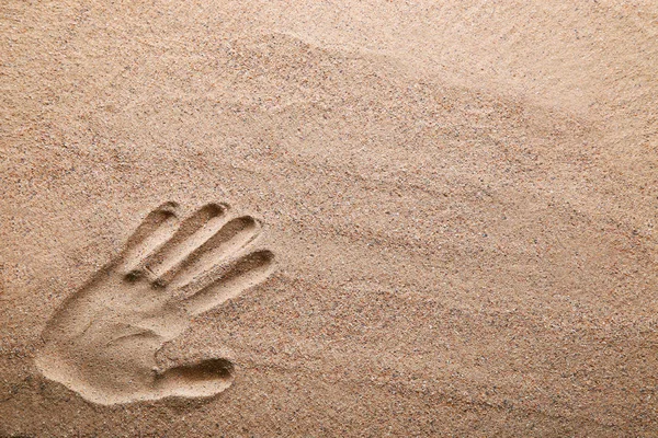 Hand print on the light beach sand