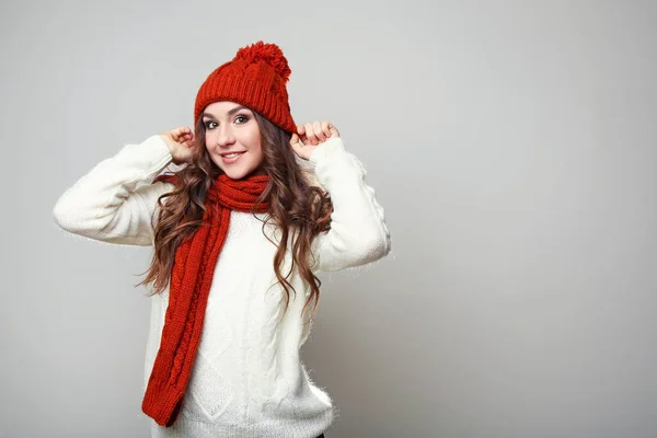 Hermosa joven en suéter, bufanda y sombrero sobre fondo gris — Foto de Stock