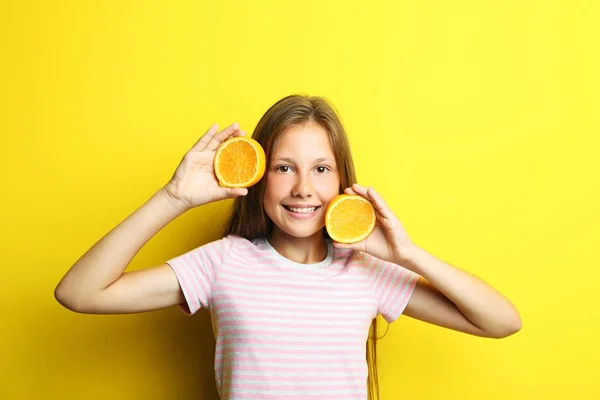 Retrato de menina bonita com fruta laranja no fundo amarelo — Fotografia de Stock