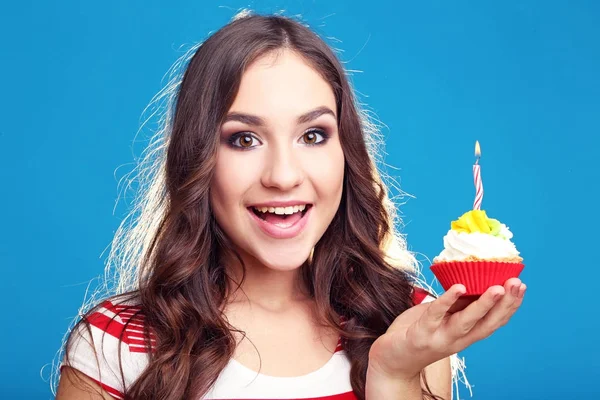 Ung kvinna med cupcake i handen på blå bakgrund — Stockfoto