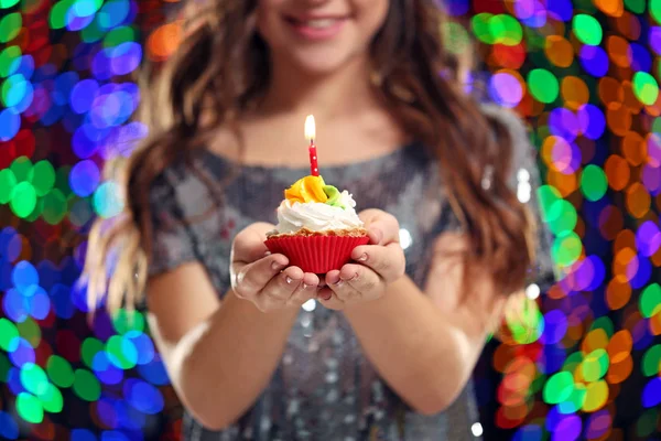 Mujer joven con cupcake sobre fondo de luces —  Fotos de Stock