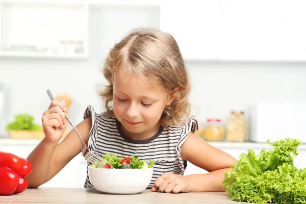 Gadis kecil makan salad di dapur — Stok Foto