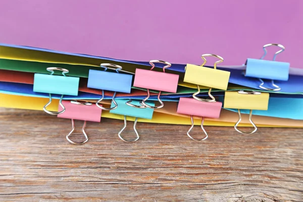 Papeles de colores con abrazaderas en mesa de madera —  Fotos de Stock