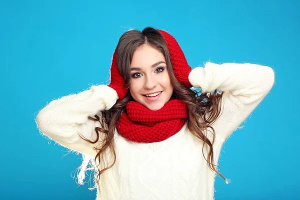 Beautiful young girl in sweater, red gloves and scarf on blue ba — Stock Photo, Image