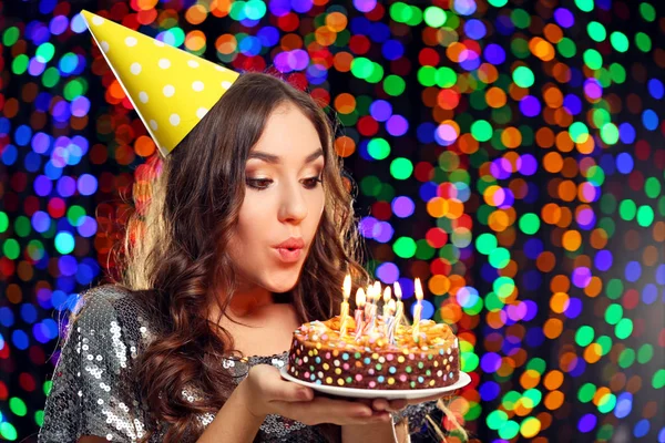 Junge Frau bläst Kerzen auf Geburtstagstorte aus — Stockfoto