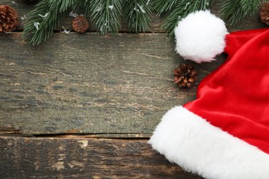 Kırmızı santa şapka köknar ağacı dalı ve koniler gri ahşap tablo