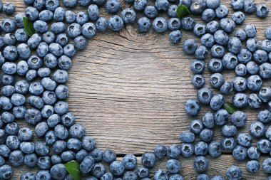 Olgun yaban mersini ile yeşil yapraklar üzerinde ahşap masa