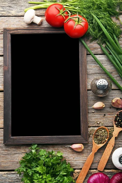 Black wooden frame with vegetables and spices on grey table