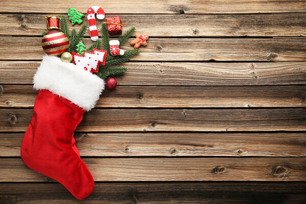 Red stocking with fir-tree branches and christmas decorations on wooden table