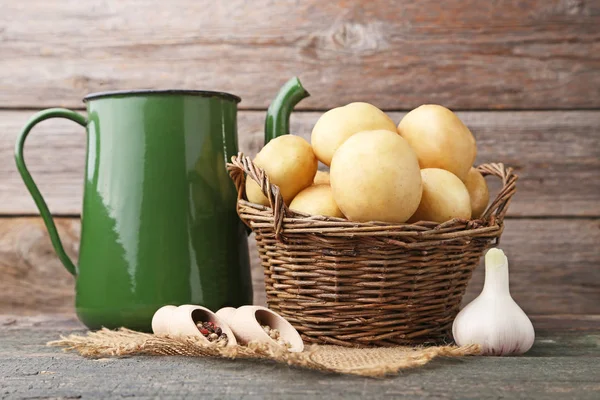 土豆在柳条篮子里有辣椒和大蒜对木制背景 — 图库照片