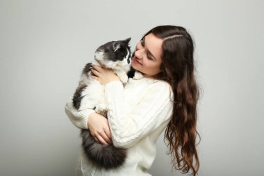 Güzel ve genç birbayan holding kedi gri arka plan üzerinde