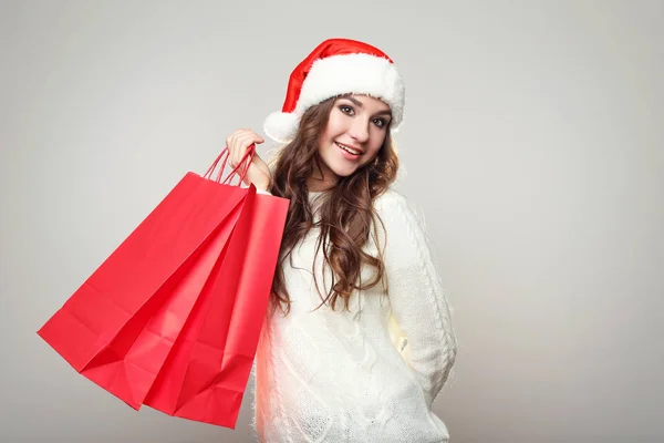 Jonge Vrouw Kerstmuts Met Boodschappentassen Grijze Achtergrond — Stockfoto