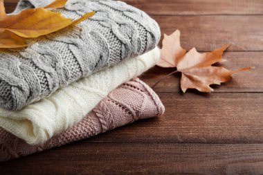 Sonbahar ile örme kazak yığını üzerinde ahşap masa yapraklar