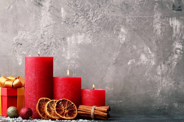 Christmas candles with gift box and baubles on wooden table