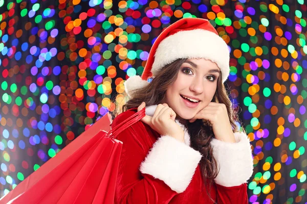 Jonge Vrouw Kerstmuts Met Boodschappentassen Achtergrond Verlichting — Stockfoto