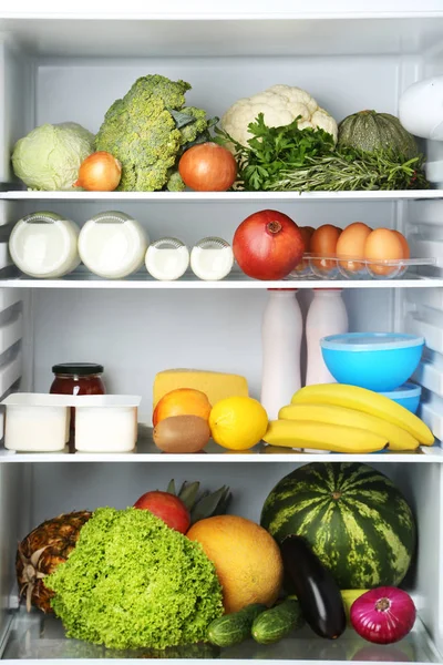 Open fridge full of vegetables and fruits