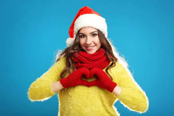美丽的年轻女孩在黄色毛衣 围巾和圣诞老人帽子在蓝色背景 — 图库照片