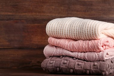 Kahverengi ahşap masa üzerinde örme kazak yığını