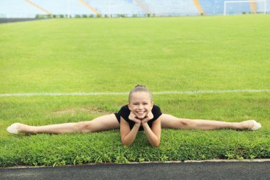Genç kız jimnastikçi yeşil çimenlerin üzerinde