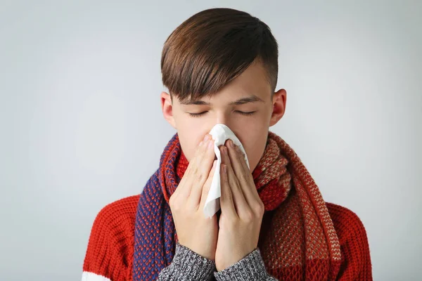 Kleiner kranker Junge mit Taschentuch auf grauem Hintergrund — Stockfoto