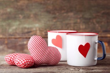 Ahşap masa üzerinde kumaş yürekleri çay kupaları