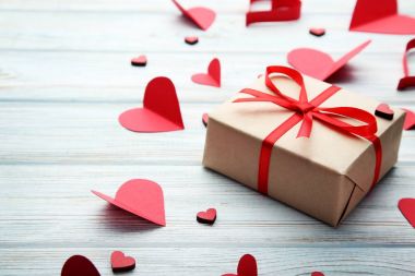 Tahta masada kırmızı kalpler olan hediye kutusu.