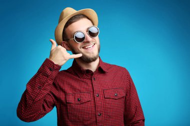 Güneş gözlüğü ve şapka mavi arka plan ile genç adam portresi