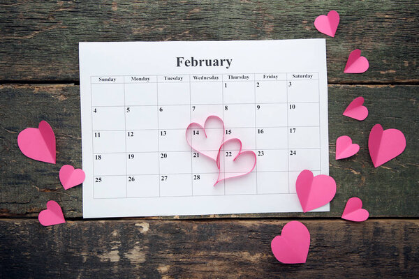 Pink hearts with february calendar on wooden table