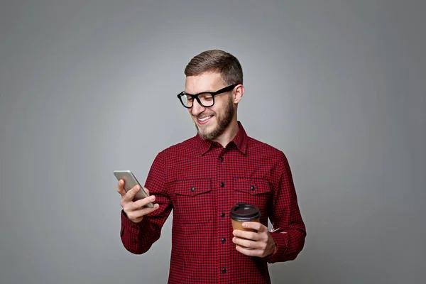 年轻人与智能手机和咖啡杯的灰色背景 — 图库照片
