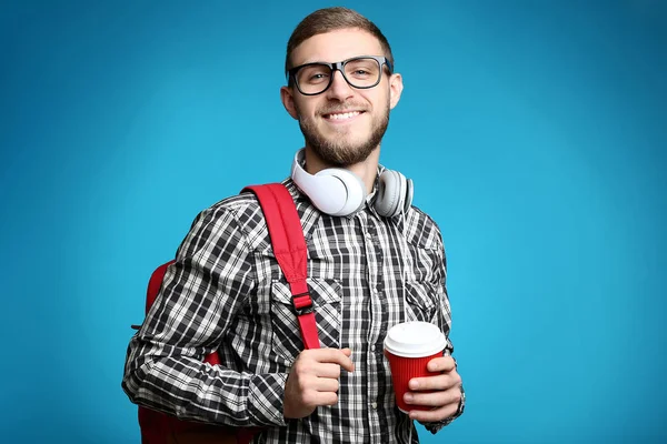 年轻人与背包 耳机和杯子咖啡在蓝色背景 — 图库照片