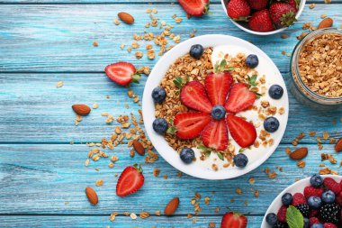 Çilek plaka üzerinde mavi ahşap masa ile lezzetli granola