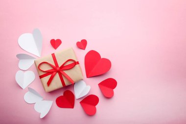 Pembe bir arka plan üzerinde kırmızı ve beyaz yürekleri hediye kutusu