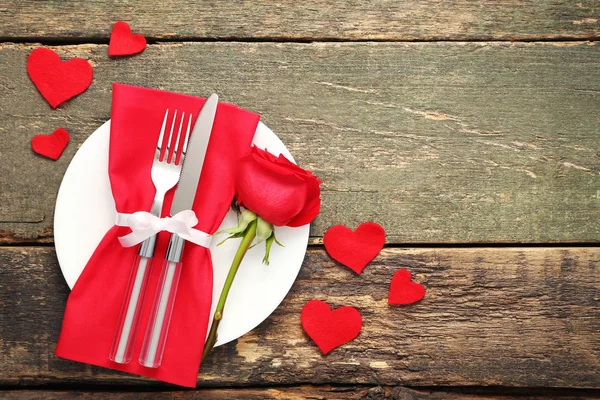 フォークとナイフの木製のテーブルの赤いバラと — ストック写真