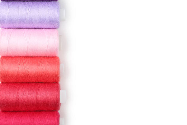 Colourful thread spools on white background