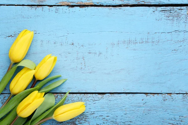 Mavi ahşap masa üzerinde Sarı laleler buket