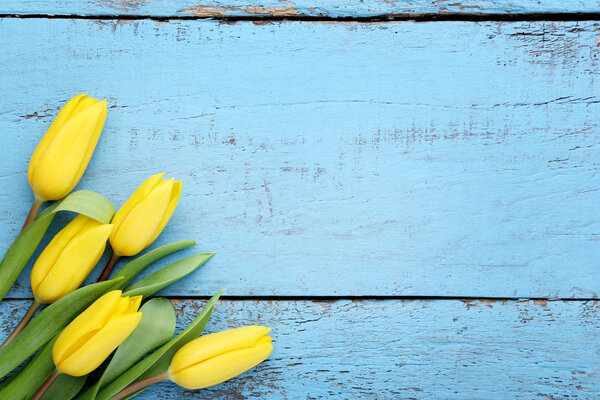 Bouquet of yellow tulips on blue wooden table