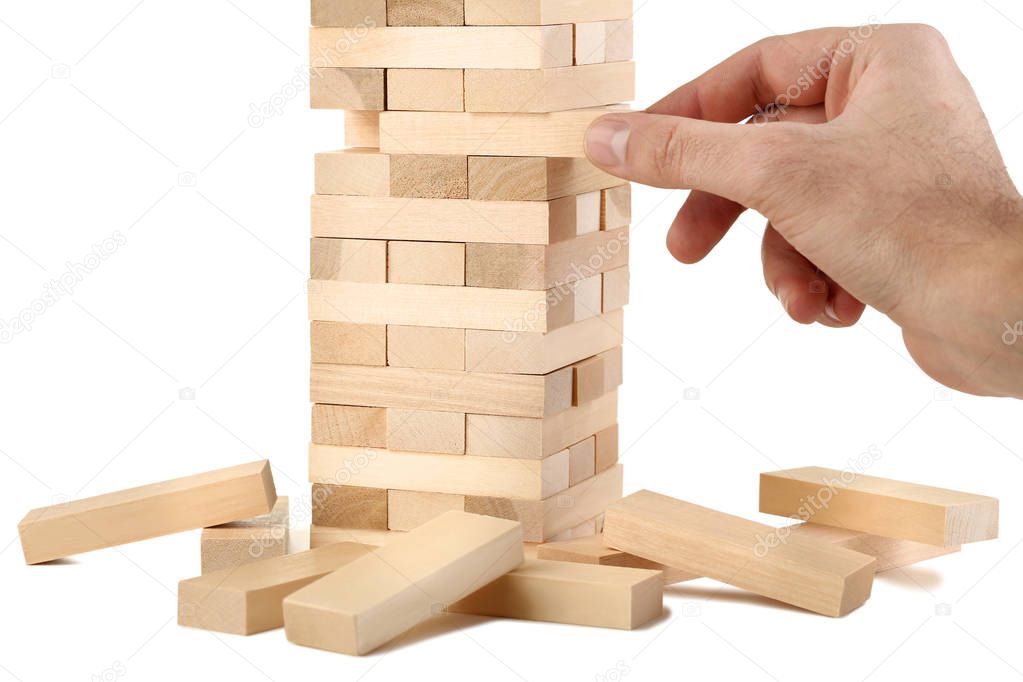 Male hand playing wooden blocks tower game on white background