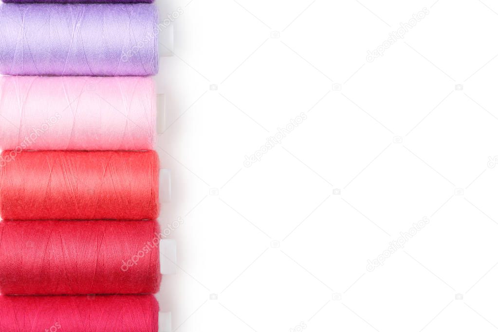 Colourful thread spools on white background