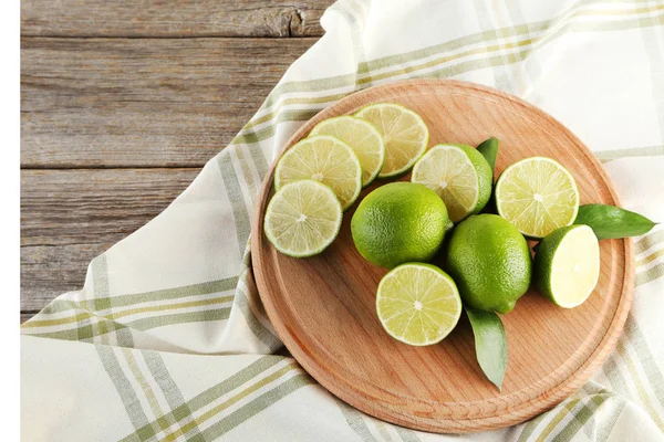Ripe limes with green leaf on wooden table