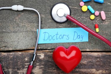 Yazıt doktorlar gün hapları, kırmızı kalp ve ahşap masa üzerinde stetoskop ile